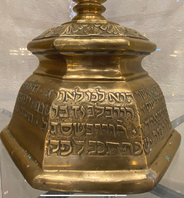 A large brass urn with hebrew writing on it.